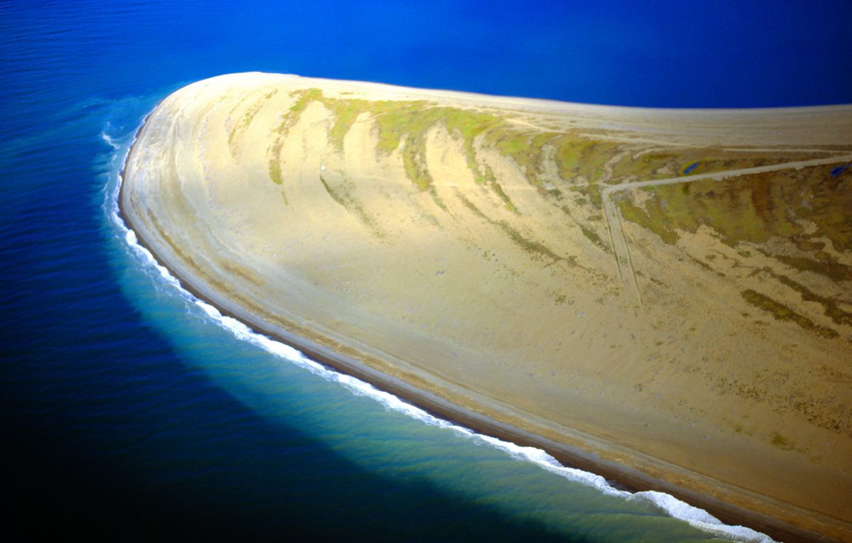 In an aerial view of the tip of Point Spencer, ridge-like dunes, deposited over time from the nearby estuary, resemble the layers of a seashell. 