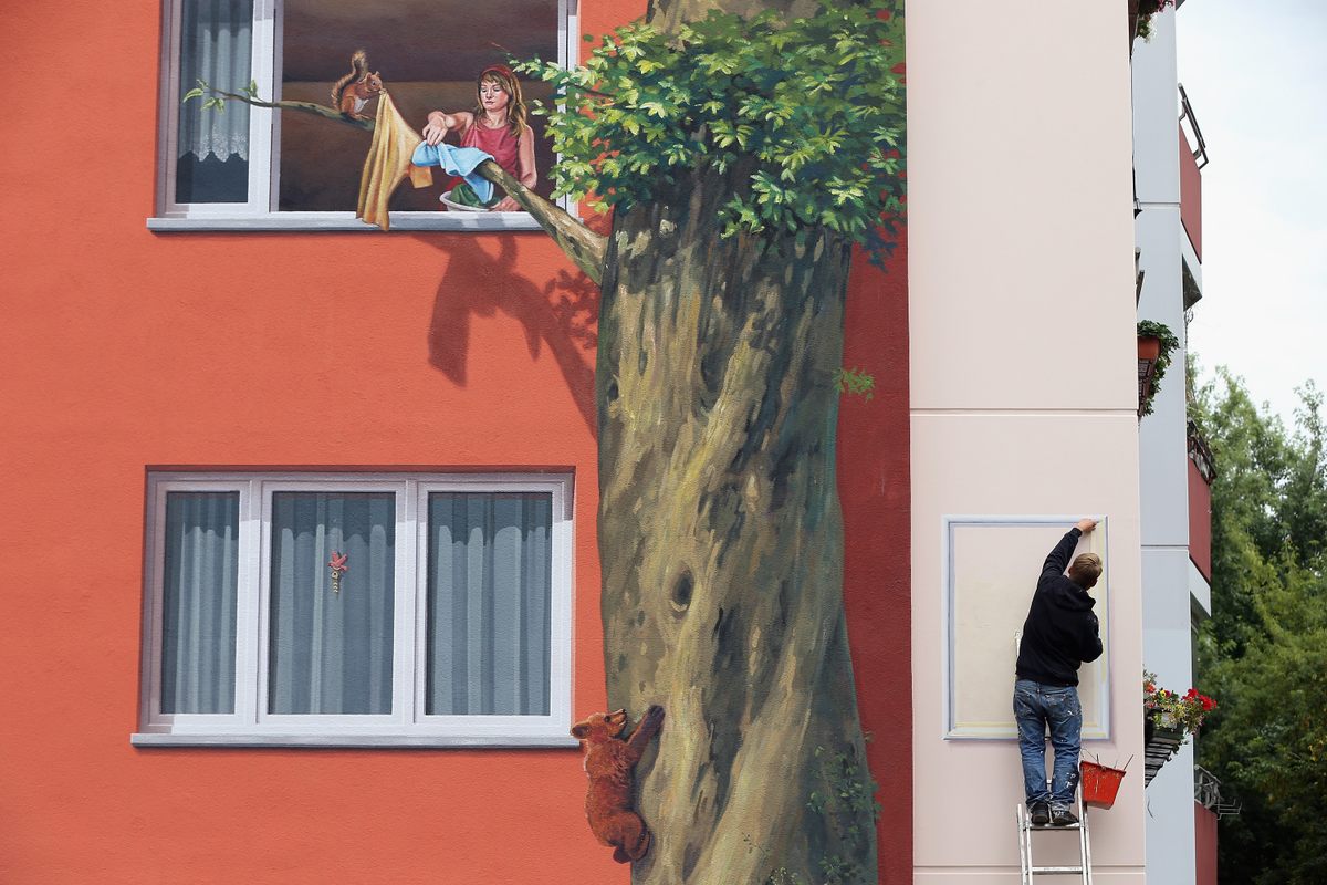 CitéCréation has expanded its work to cities around the world. Here, painter Steve Rolle puts the finishing touches on a mural at the Wohngenossenschaft Soldaritaet coop apartment buildings in Berlin.