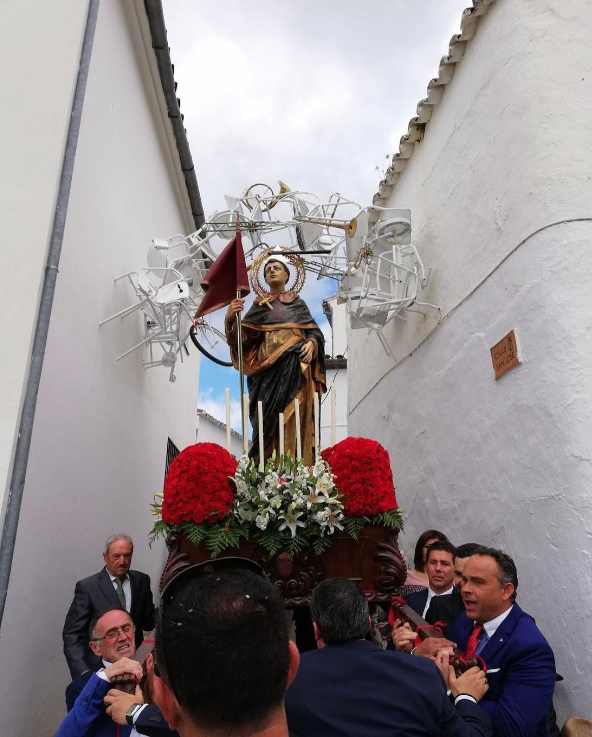 A Semana Santa parade through the village's streets passes beneath art by Isidro López Aparicio.
