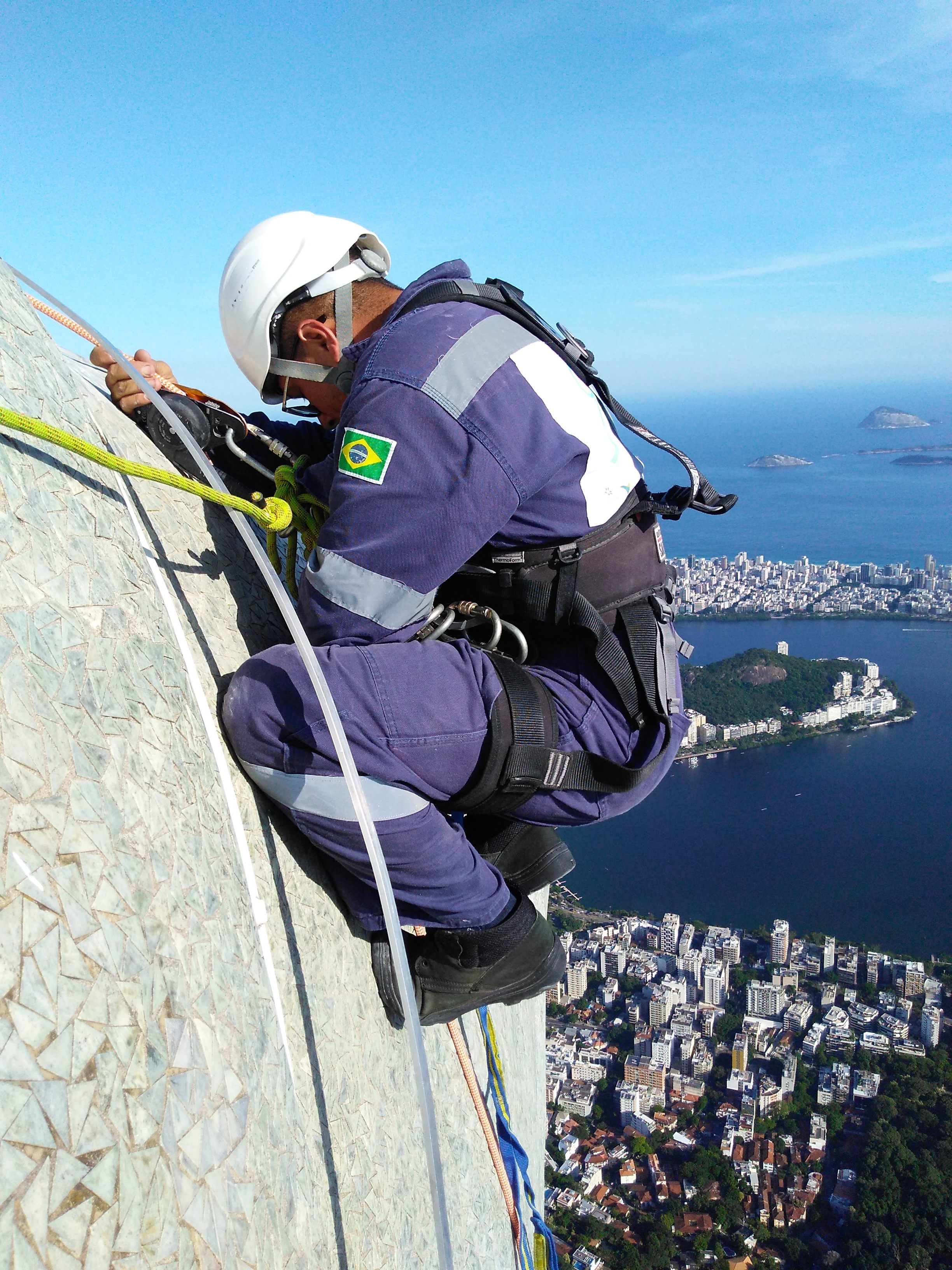 A restoration worker rappels down the side of the statue, across the triangular tiles that cover its surface. 