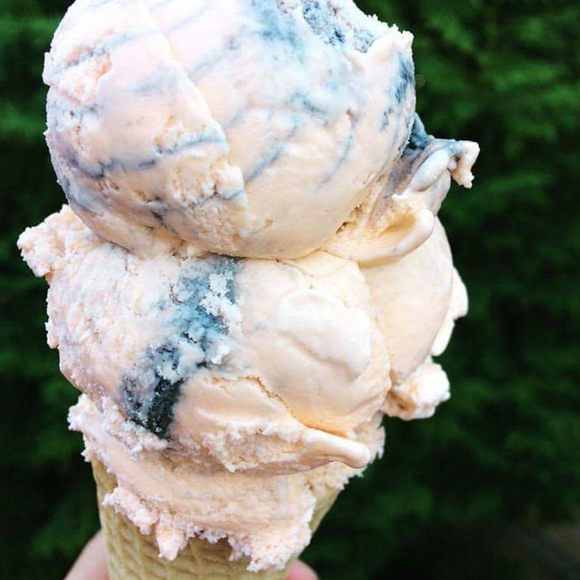 A double scoop of orange-flavored tiger tail ice cream striped with black licorice ribbons.