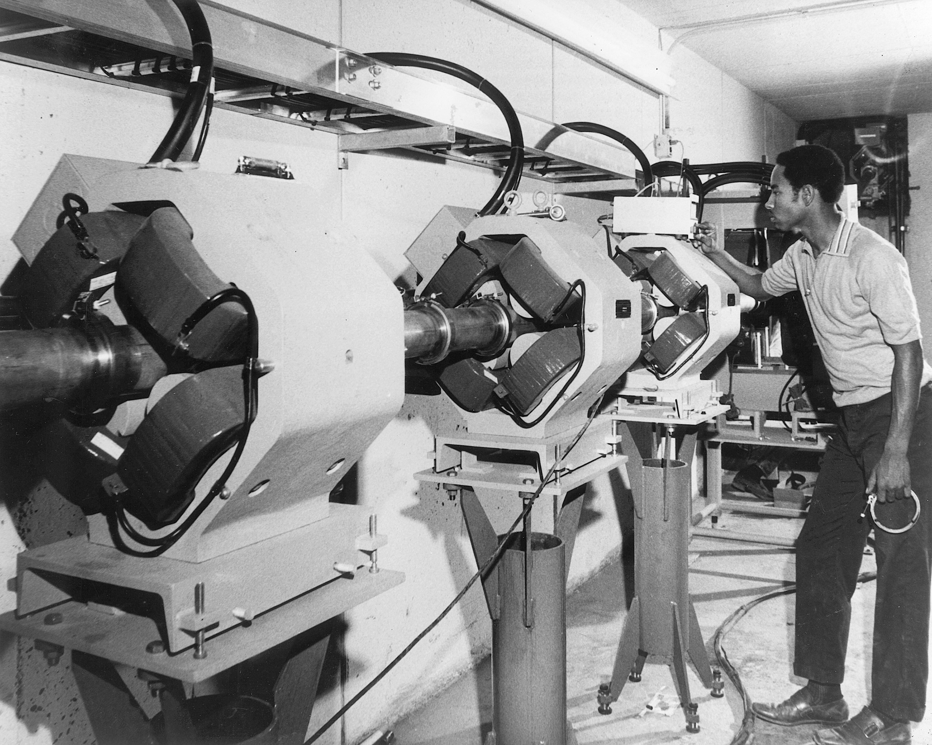 A technician checks a device that monitors the vacuum system in a section of the giant 200 BeV Synchroton being built, circa 1970.
