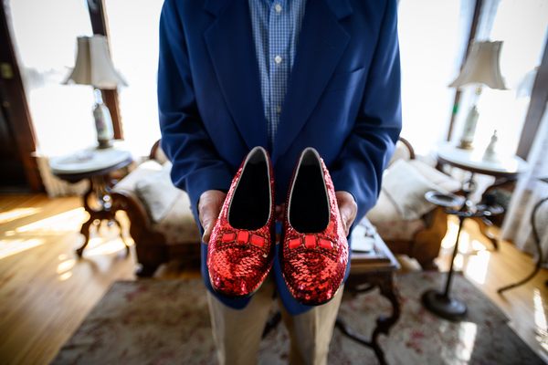 John Kelsh holding a replica of the ruby slippers in 2019.