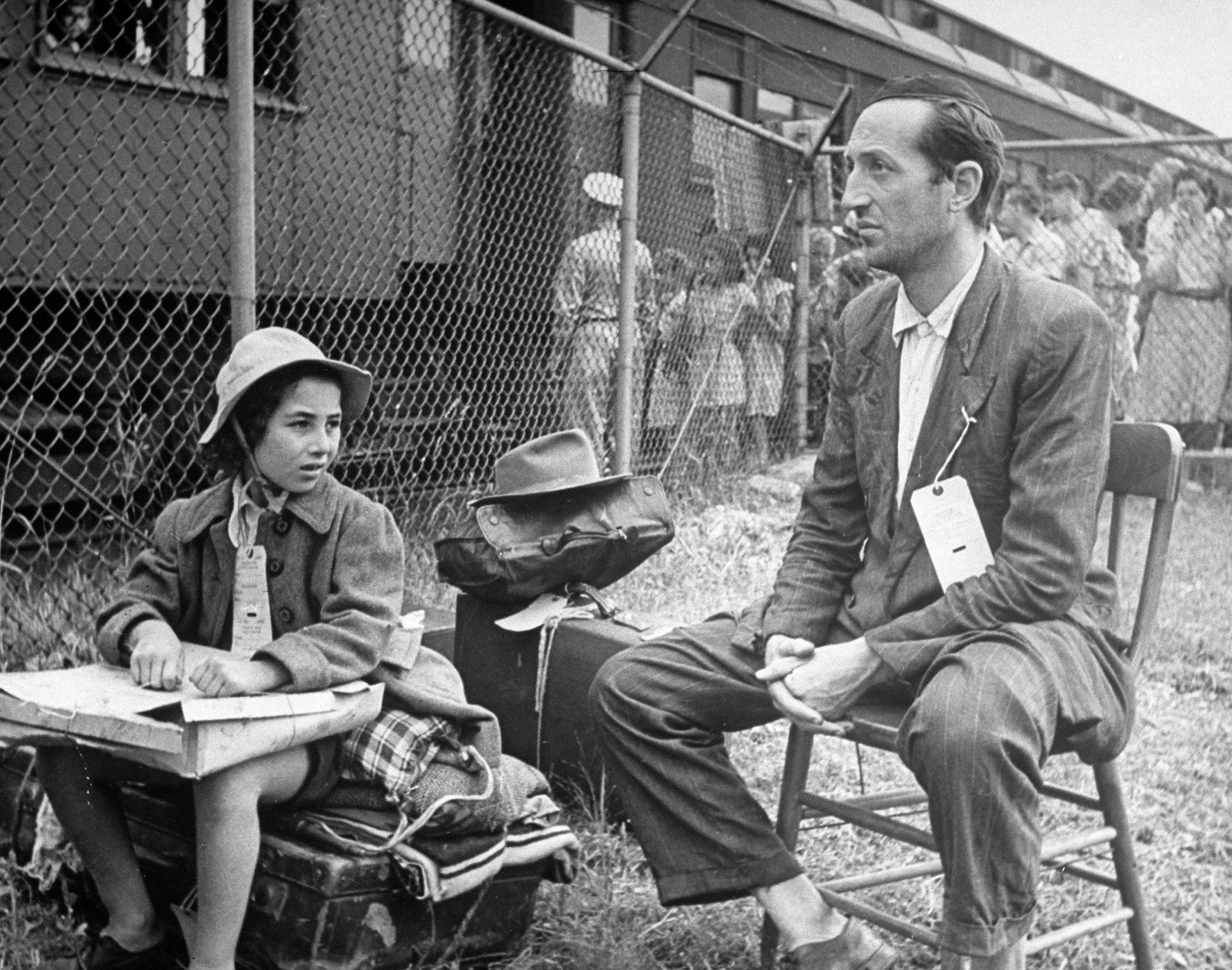 A Jewish refugee from Tripoli and his daughter at the gate of Fort Ontario.