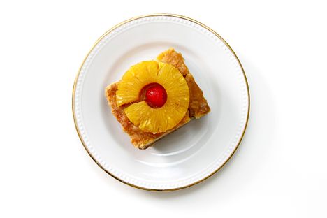 A maraschino cherry adorns a slice of pineapple upside down cake.