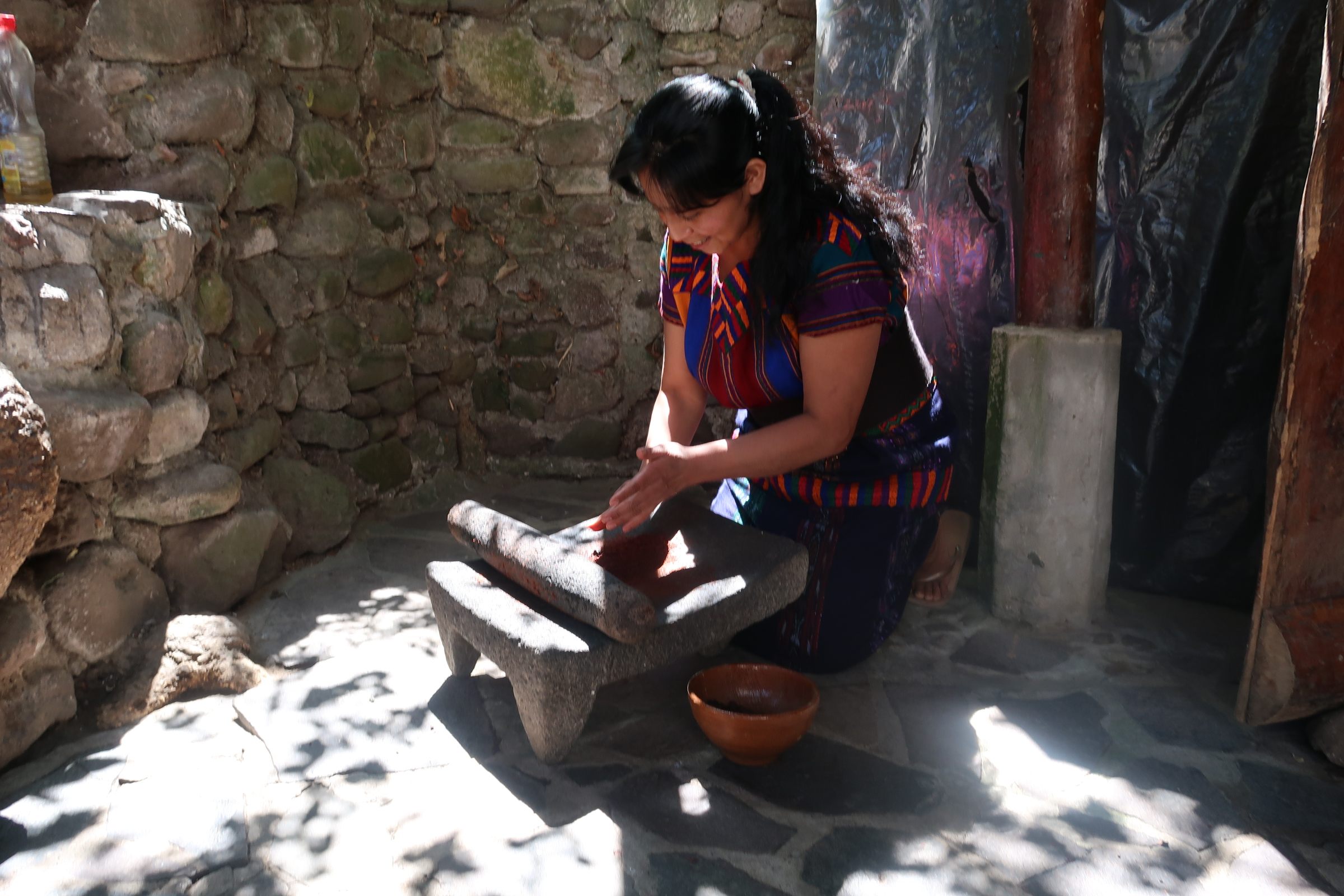 Maria Mendoza Sac shows how to grind beans the ancient way.