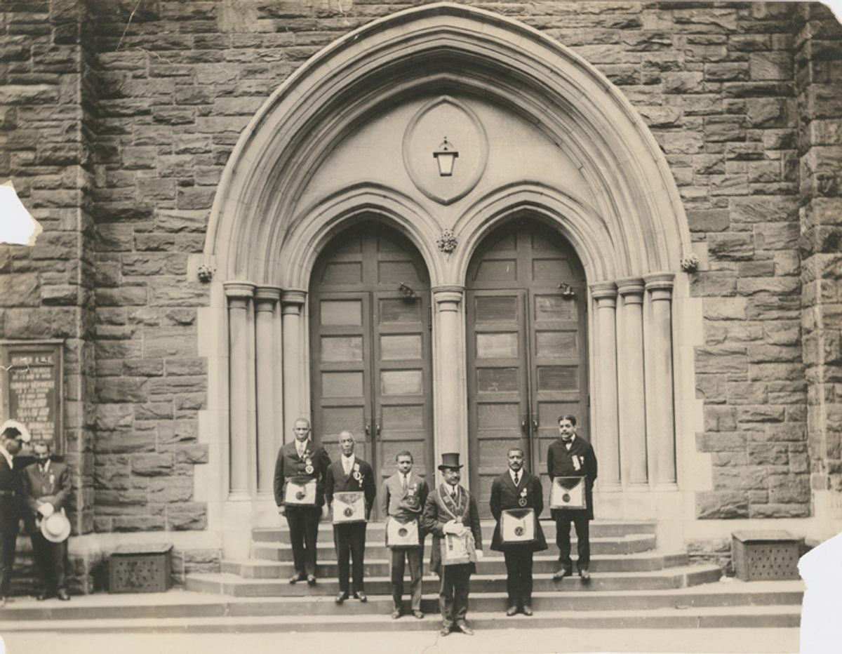On the far right, Schomburg stands on the steps of Harlem's Mother A.M.E. Zion Church, along with members of the Prince Hall Grand Lodge.