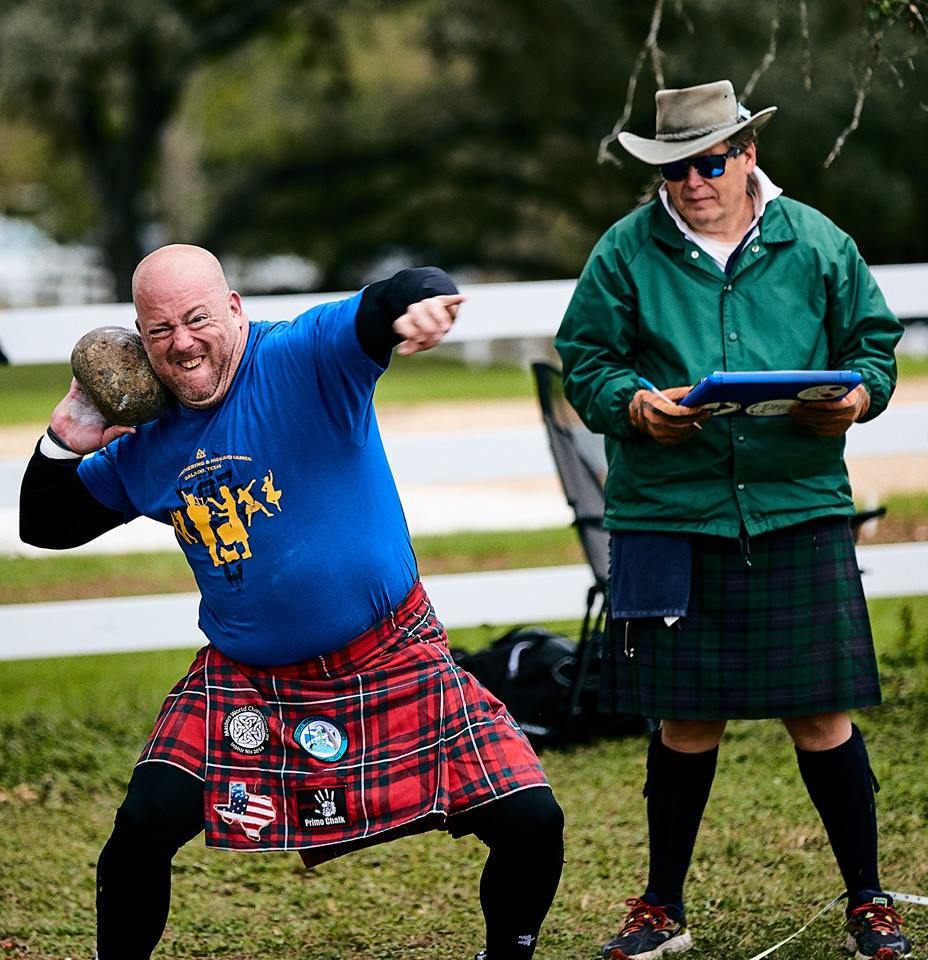 A strong lad gets ready to toss a very heavy stone.