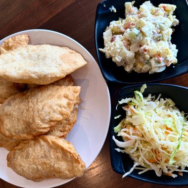 Fried, meat-filled khuushuur pastries with two kinds of chilled salad.