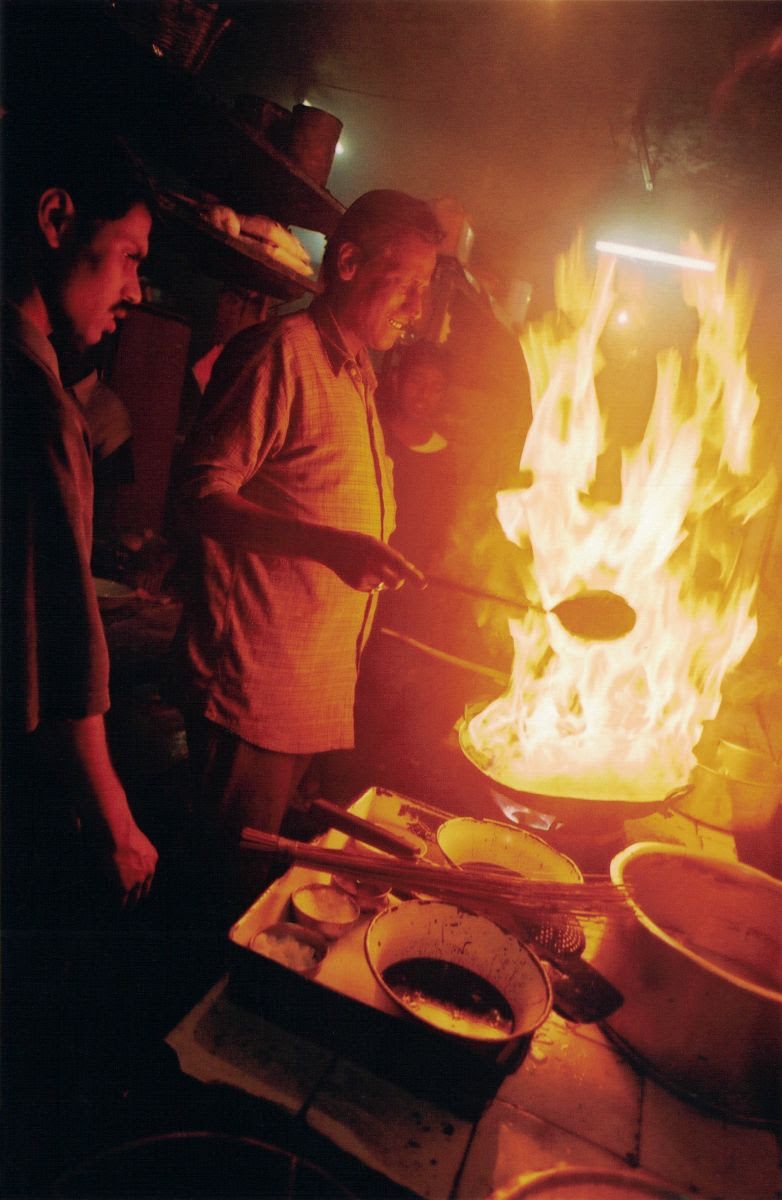 A man handles a flaming wok in Hotel Valentino in Darjeeling, India. 