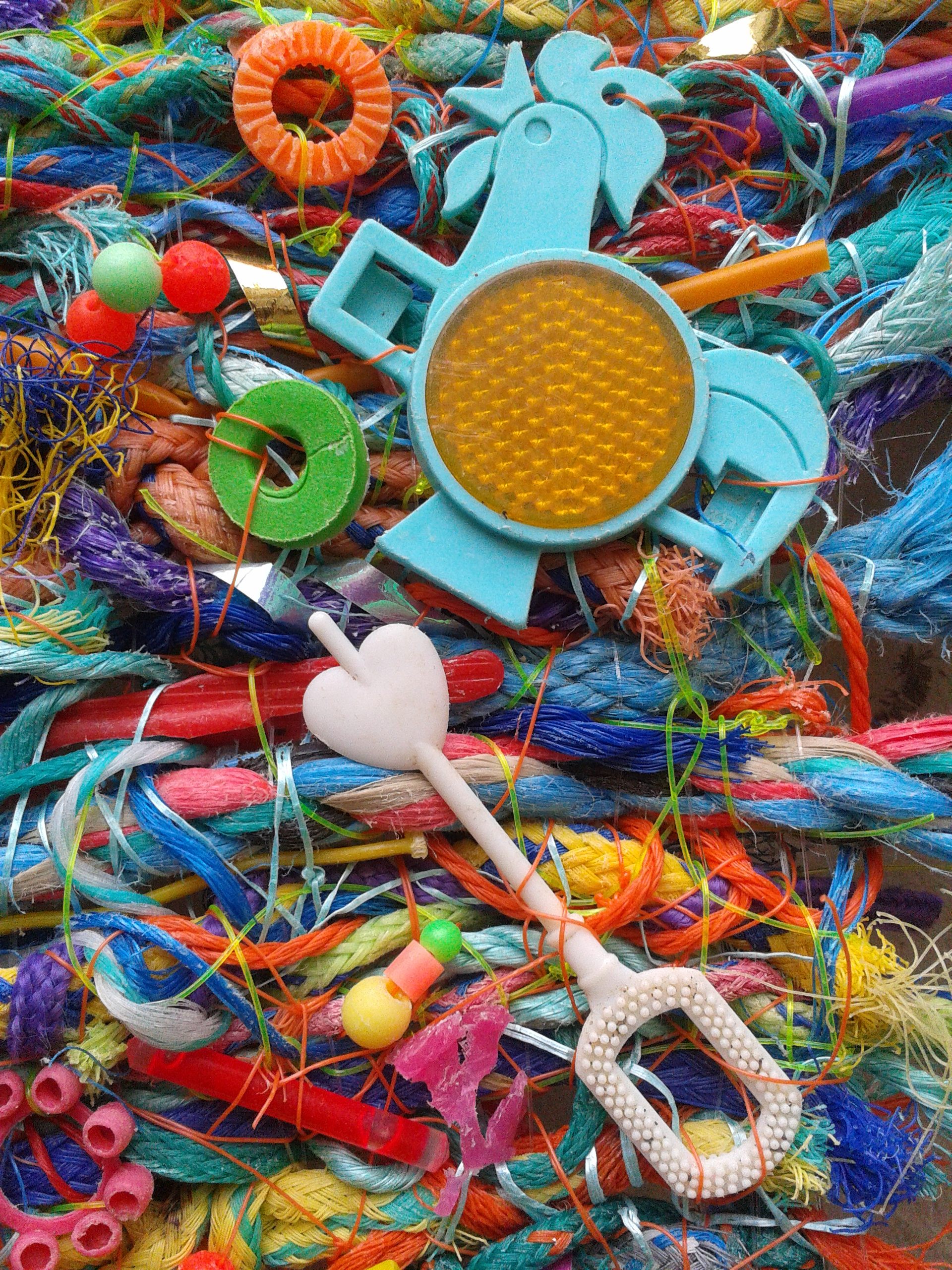 A detail from a flotsam weaving, featuring a bubble wand and a rooster-shaped bike reflector that once came free in boxes of Kellogg's Cereal.