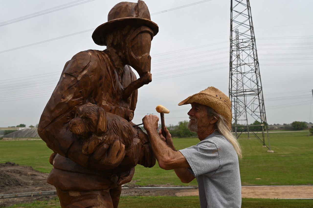 Artist Jimmy Phillips puts finishing touches on a sculpture made from a diseased oak tree in League City, Texas. 