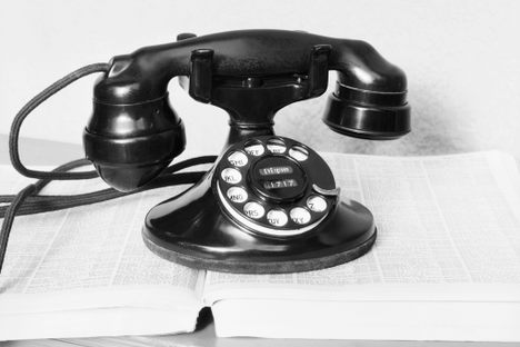 An old rotary dial telephone resting on a directory, c. 1930s. 