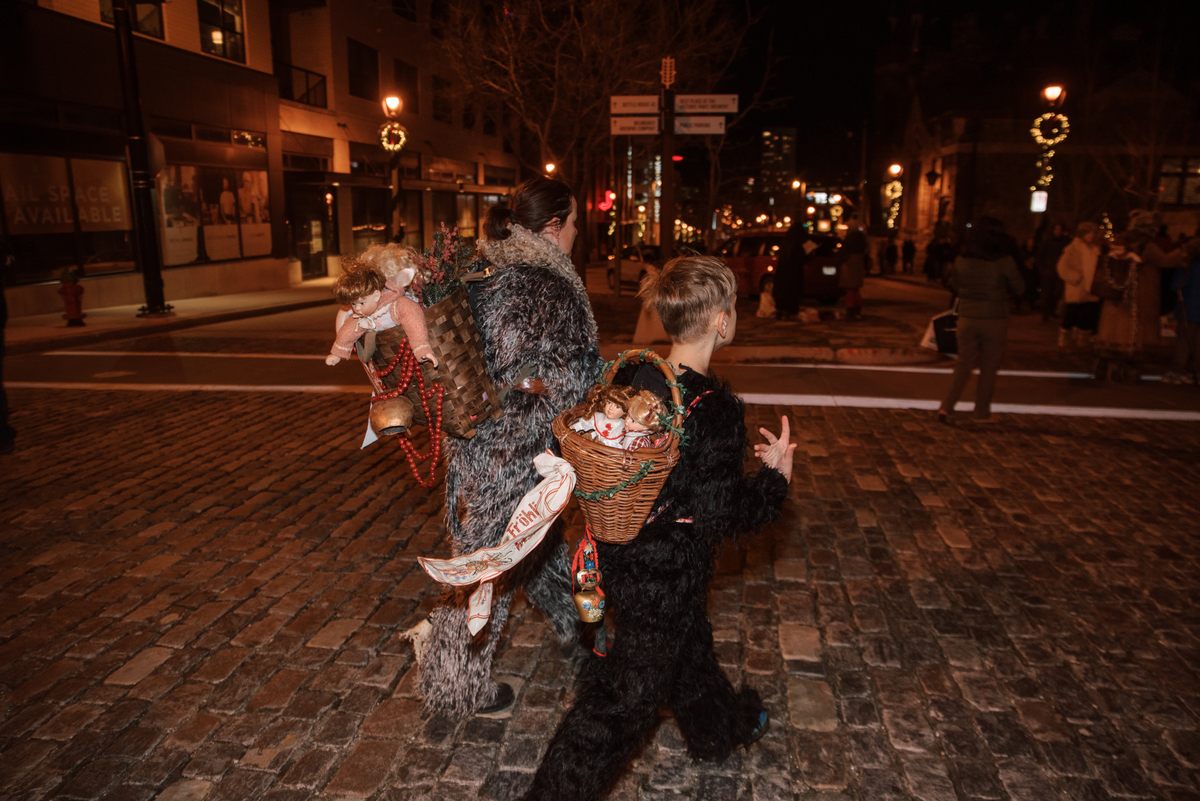 A mother and son in their costumes, including baskets full of stand-ins for the naughty children sometimes carried off by Krampus.