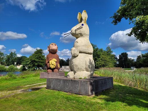 A 15 foot tall white bunny sculpture on a grey pedestal in a park