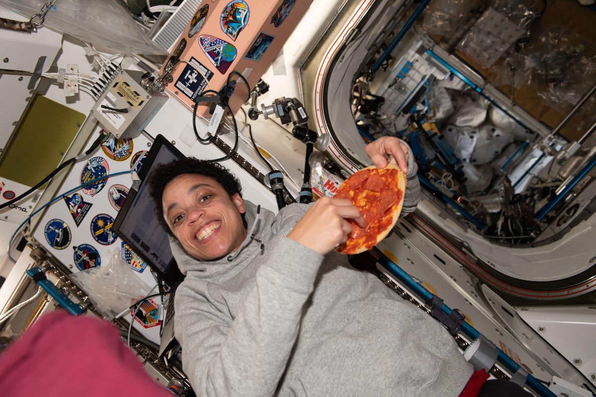 Flight engineer Jessica Watkins poses with a pizza aboard the ISS in 2022.