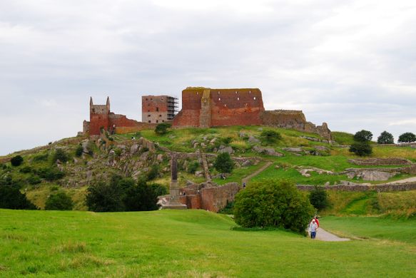 Red-stone castle ruins sit atop a green hill