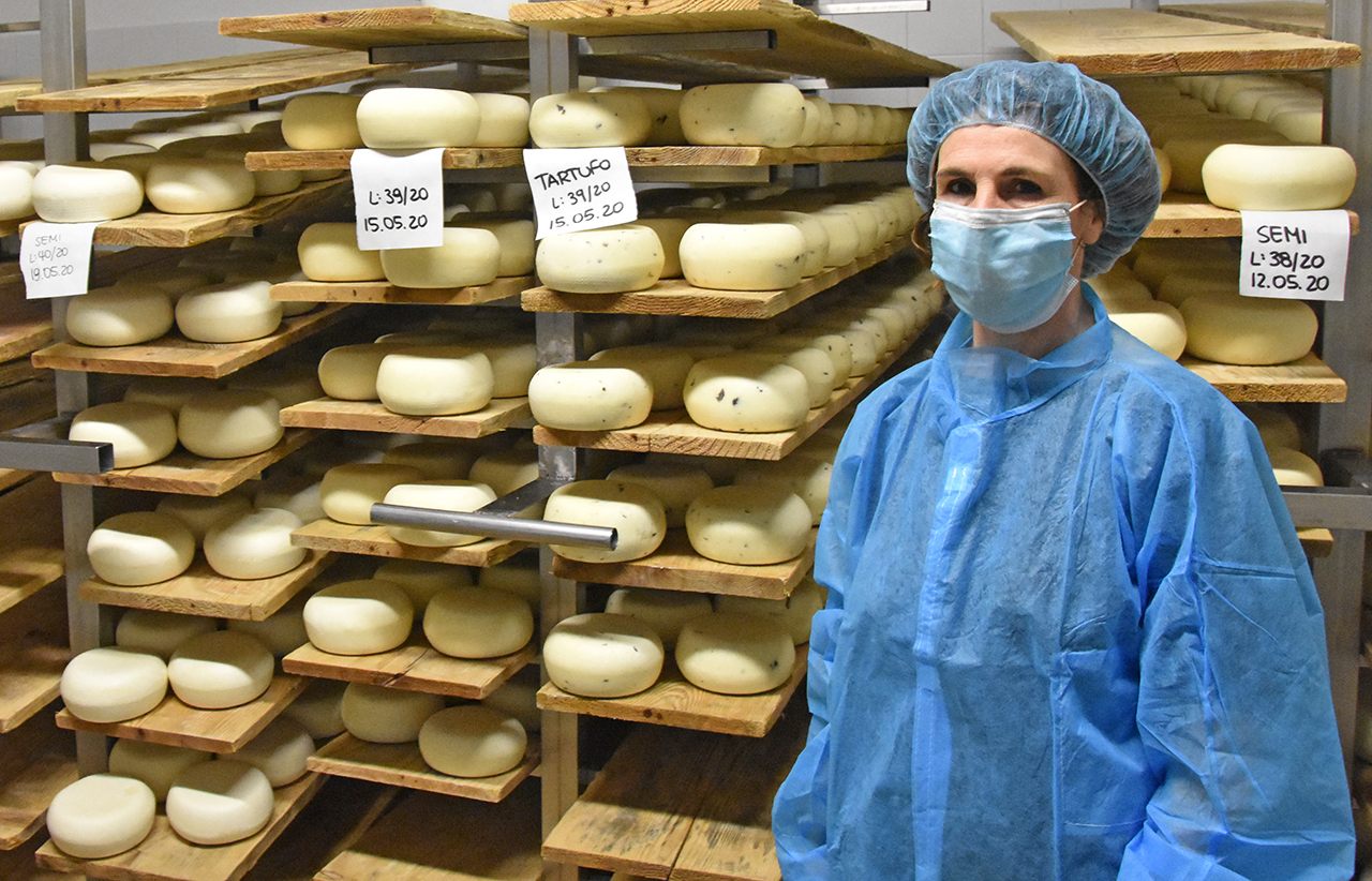 Silvana Cugusi, the daughter of a Sardinian shepherd who migrated to Tuscany in 1962, stands next to cheese wheels.