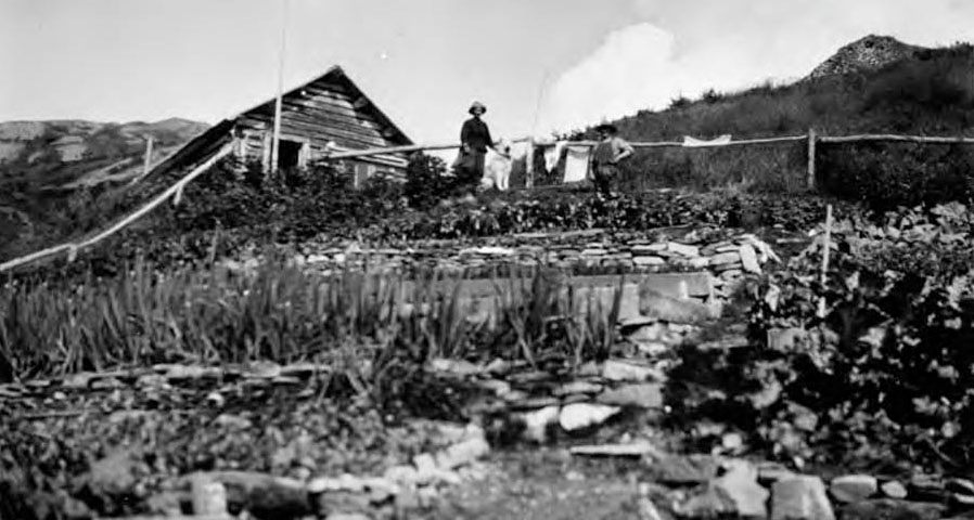 Fannie Quigley standing in front of her cabin. 