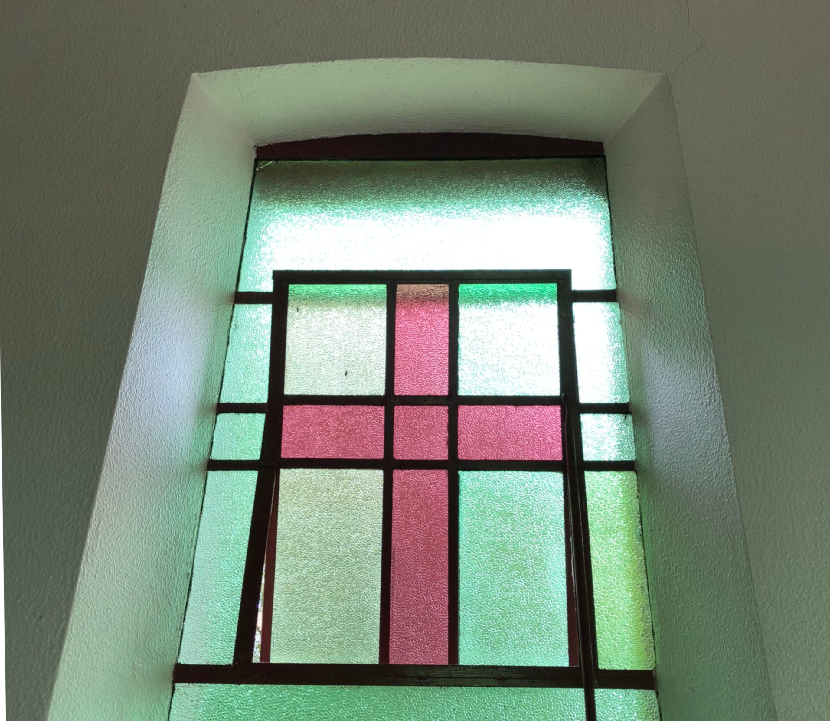 A wine-colored cross in the chapel's stained glass.