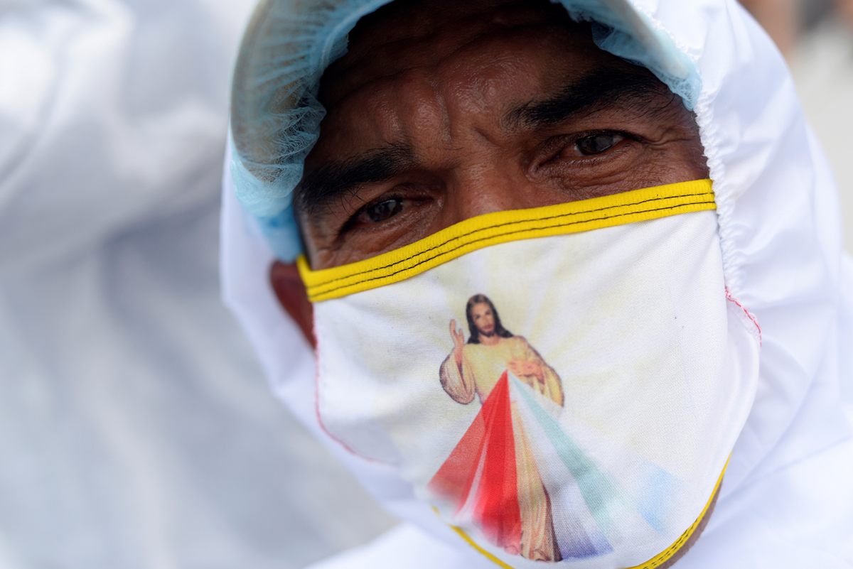 A funeral worker in Guayaquil, Ecuador, wears a face mask depicting Jesus, April 15, 2020.
