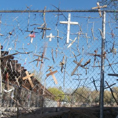 Crosses on fence in parking lot.