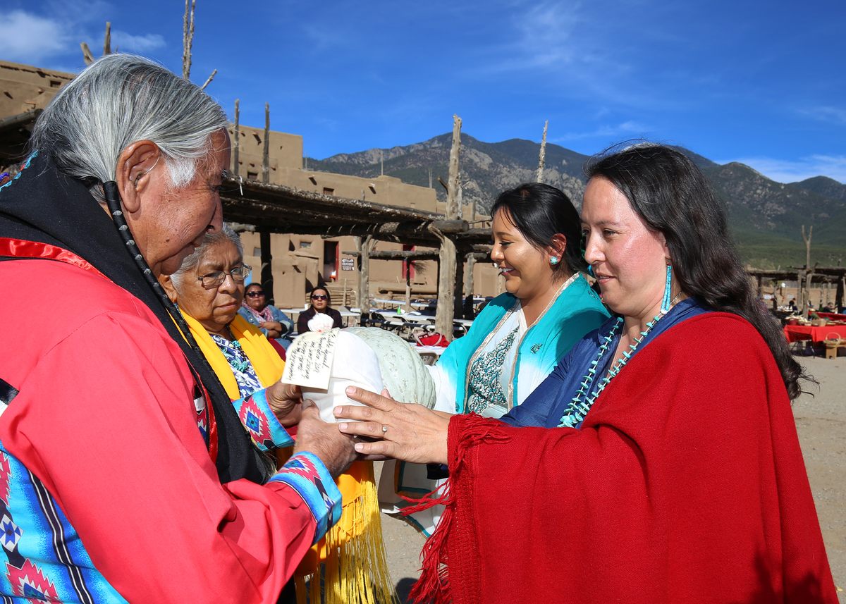 Former Taos governor Gilbert Suazo, Sr., receives a bundle of Taos Pueblo squash from Rowen White, chair of the board at Seed Savers Exchange and Indigenous seed keeper.