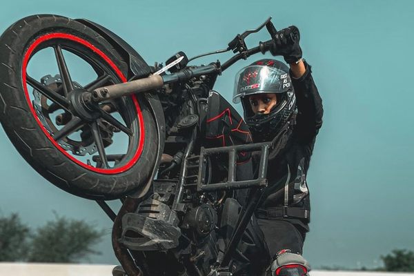 Tana Luciya Joji practices a wheelie on a quiet stretch of asphalt in Kerala, India.