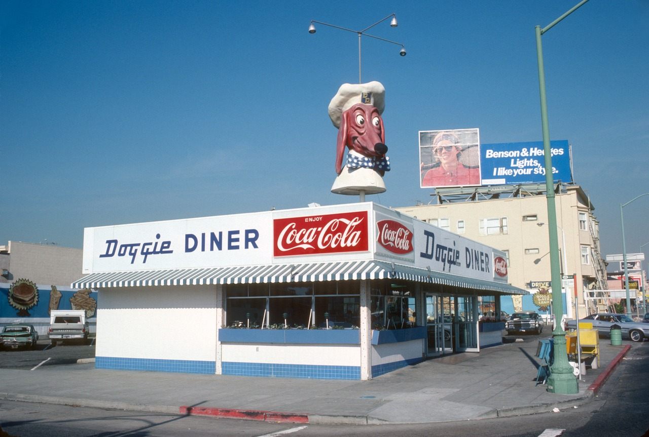 An original Doggie Diner back in the day, flanked by period cars and ads.