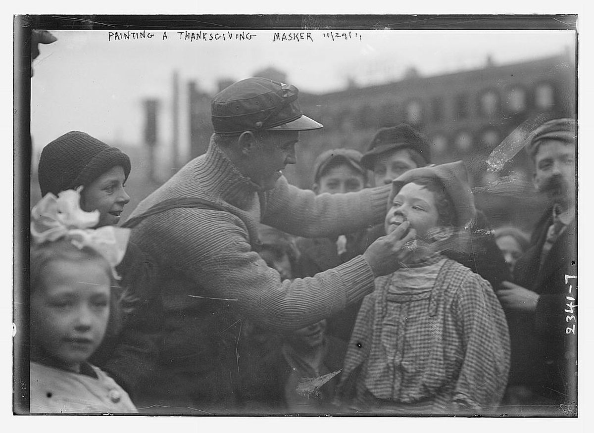 A masker gets his face painted for the 1911 parade.