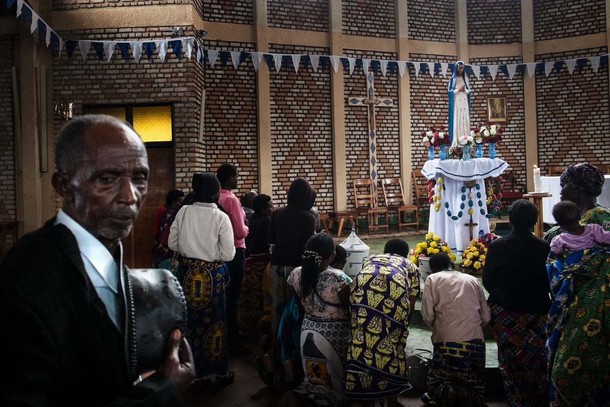 People pray in front of Our Lady of Kibeho in the shrine. The statue reflects the characteristics offered by the recognized seers of the vision: incomparably beautiful, neither white nor black, clad in a white dress and a wide, sky-blue veil.
