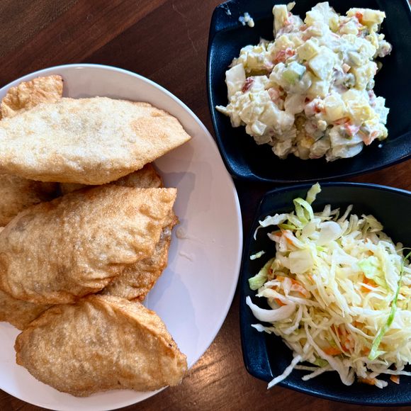 Fried, meat-filled khuushuur pastries with two kinds of chilled salad.