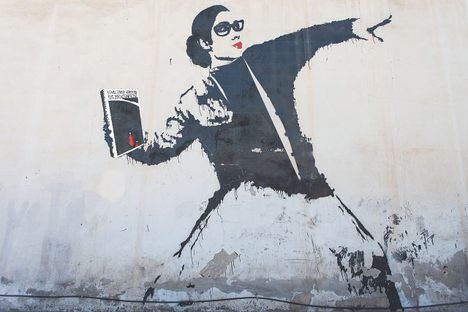 An adaptation of Banksy's "Flower Bomber," this depicts a librarian in protest, throwing Margaret Atwood's A Handmaid's Tale.