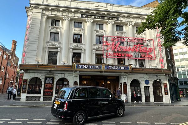 The white exterior of a Victorian theater with red neon lettering 