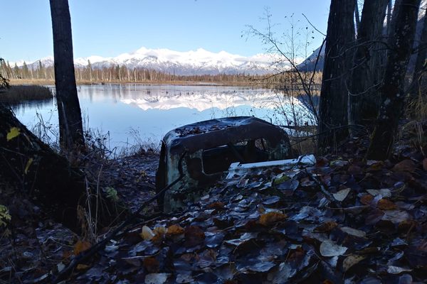 The old cars look out over the Knik River to the Talkeetna Mountains.