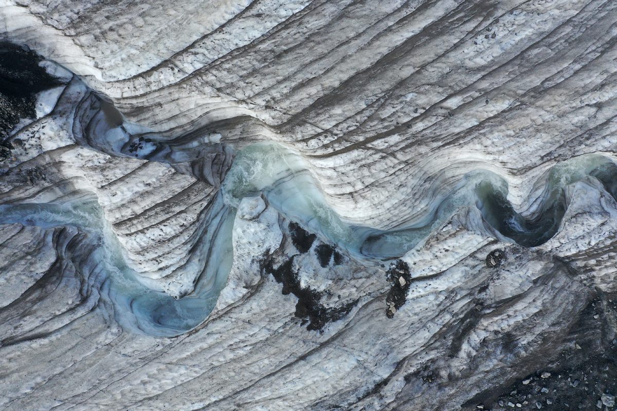 Water carves a winding channel down the surface of the melting Longyearbreen Glacier on Norway's Svalbard archipelago during a summer heat wave (July 2020). 