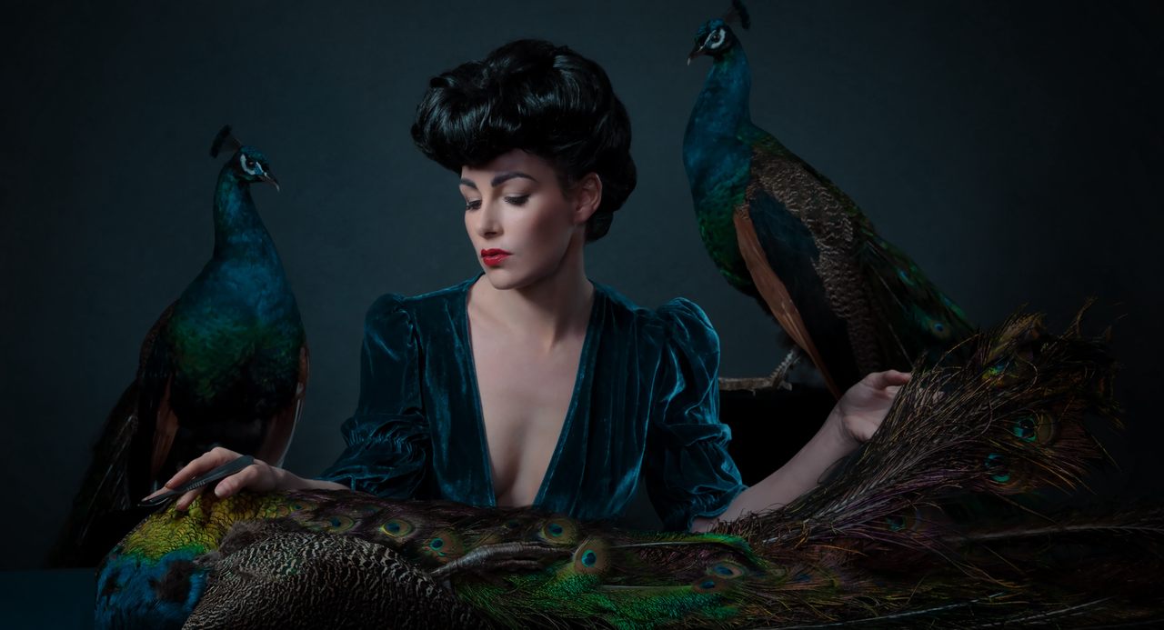Atlas Obscura instructor Allis Markham poses with two taxidermied peacocks.