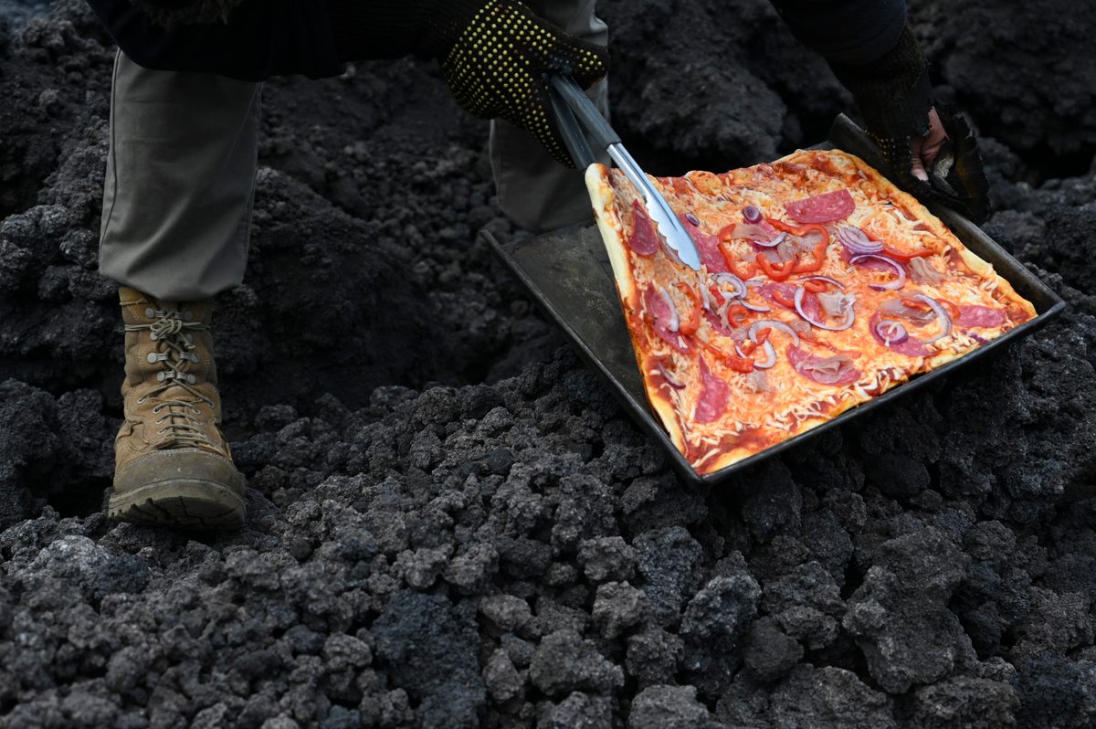 Innovative chef David Garcia checks a pizza he is cooking on a lava river from the Pacaya Volcano at Cerro Chino Hill in Guatemala, on May 11, 2021.