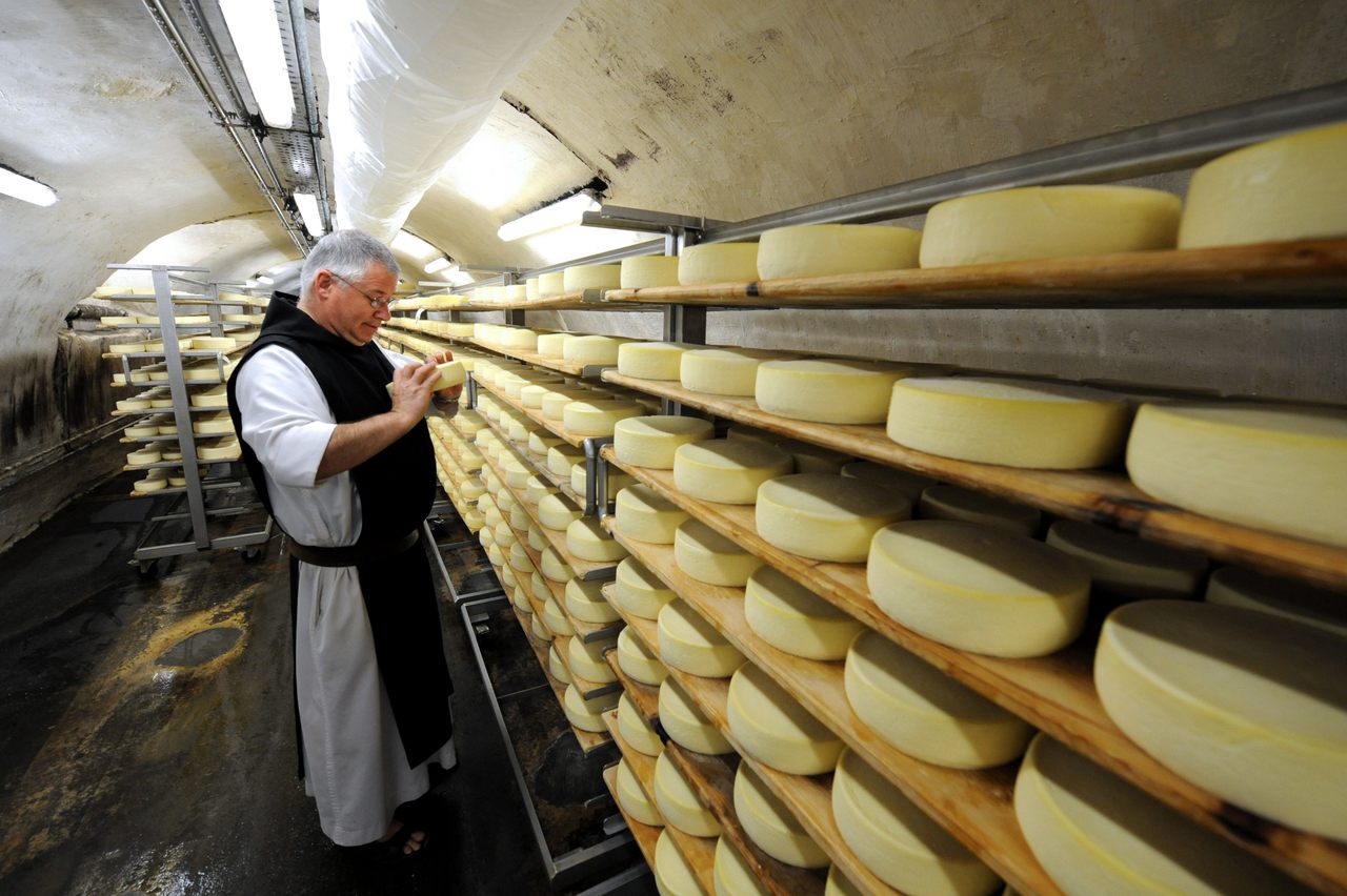 A cheesemaker monk flips around Abbaye de Tamie cheese wheels stored in the abbey's cellar.
