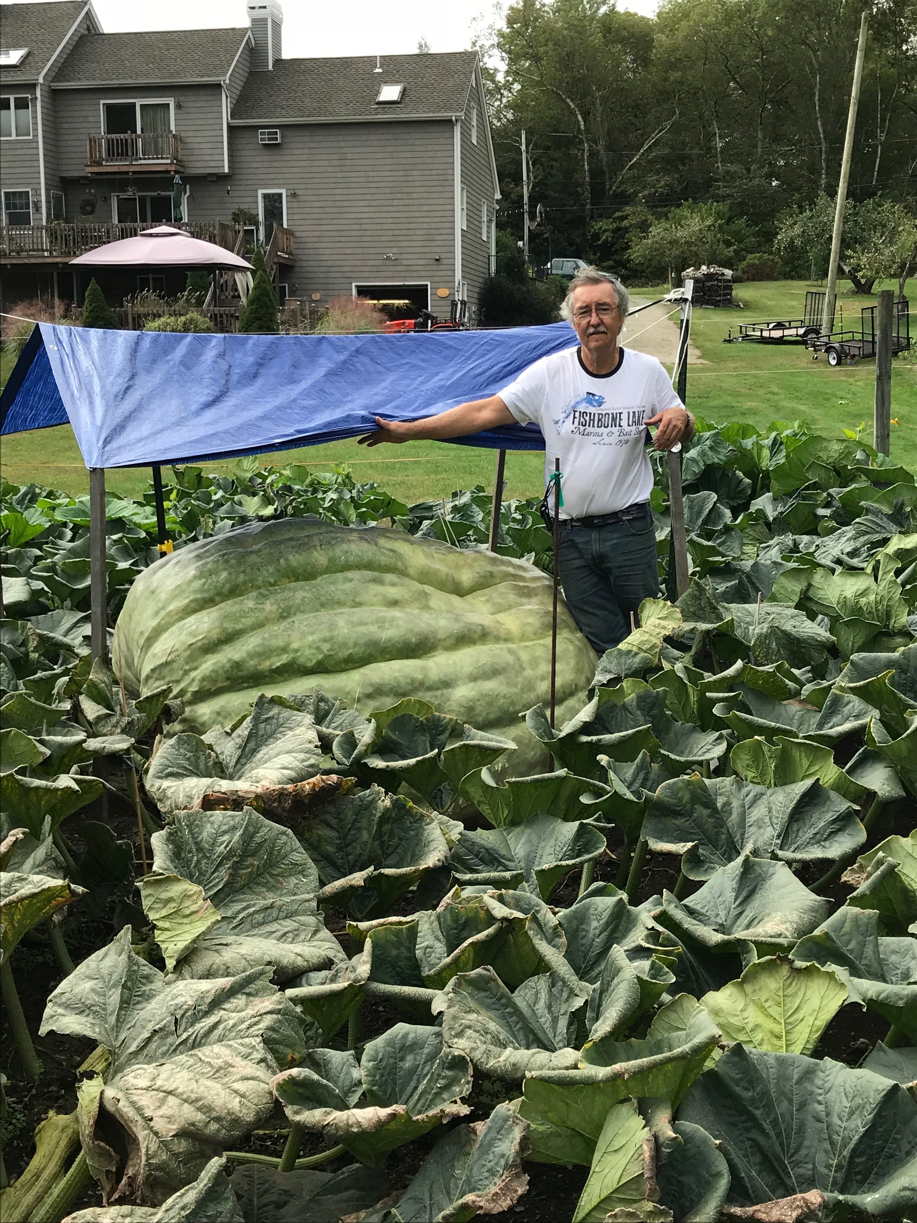 Joe Jutras stands with the green squash in his yard in North Scituate, Rhode Island.