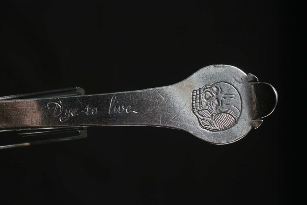 The Cromptons' spoon ends in a trefid design, with a slightly more detailed skull and "Dye to live" on its front.