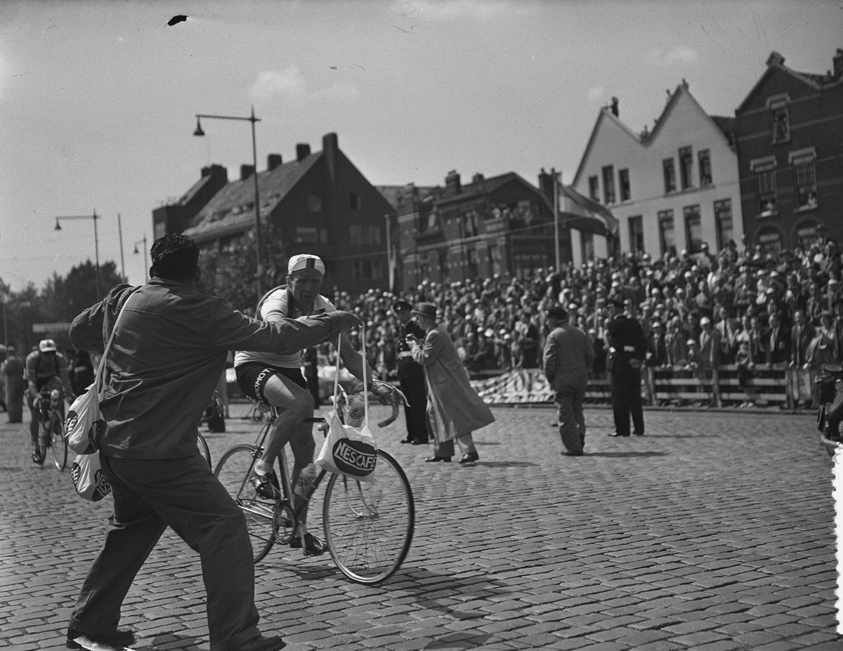 Riding through Rotterdam in the 1954 Tour, Kees Pellenaars nabs a musette.