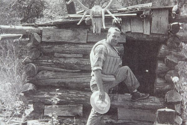A member of the Hatch-Swain-Frazier Expedition stands in front of Parrott’s Lower Cabin on the Middle Fork Salmon River in 1936. 