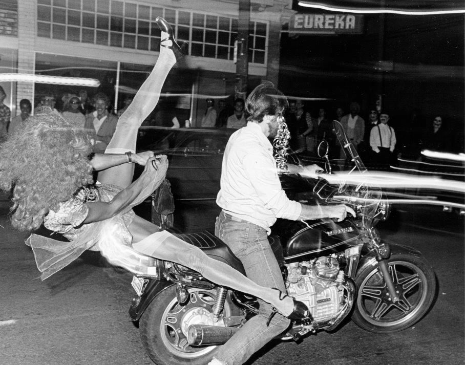Two partiers drive past the Eureka Bar, off Castro Street, on Halloween 1982.