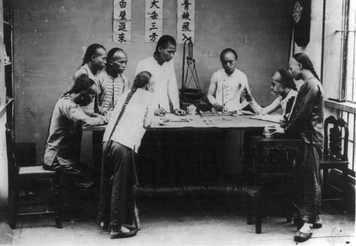 A group of men gambling together with the traditional "queue" hairstyle.