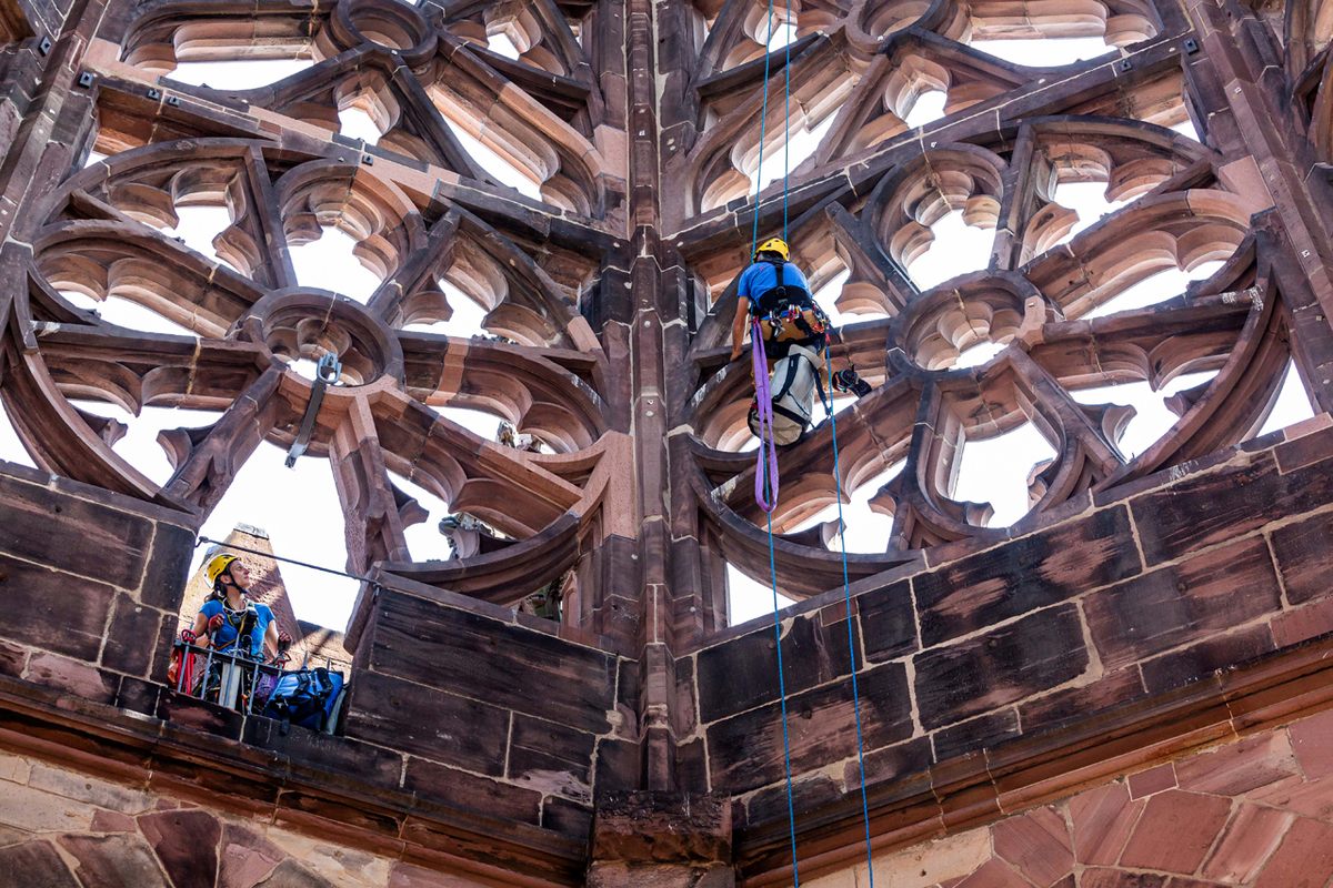 An industrial climber works along the inside of the tower, while a colleague stands in a passage from the surrounding gallery.