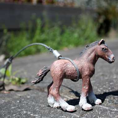 Toy horse tied to a sidewalk ring in Portland, Oregon.