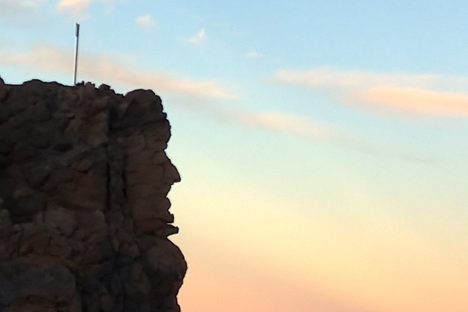 The stone man can be seen on the side of the cliff, looking out over the island.