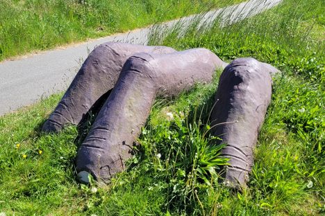 The concrete hand rises from the grassy slope.