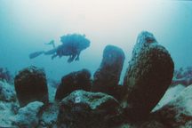 A diver passes by rock formations 